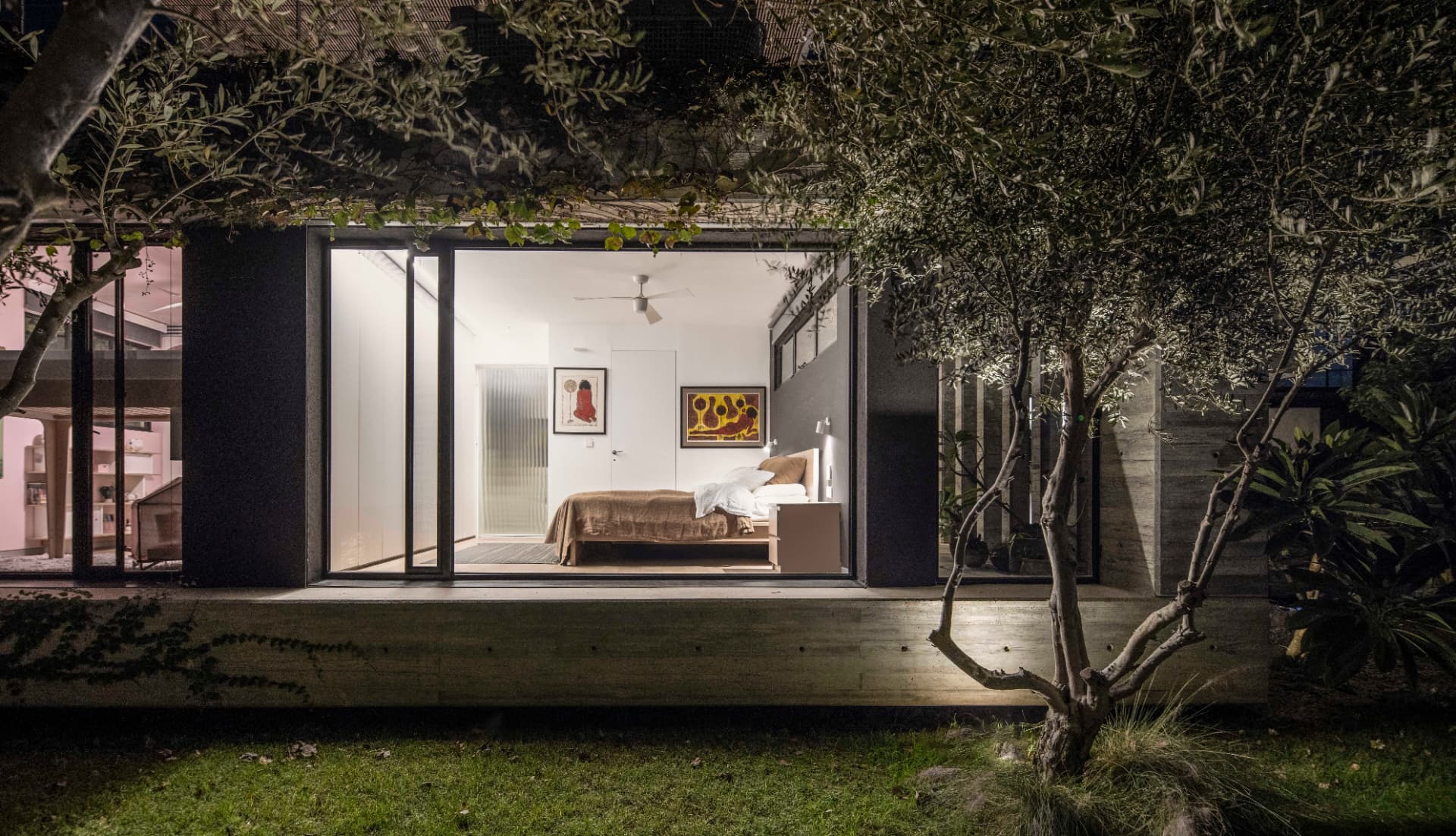 Bedroom glowing through the olive trees at night